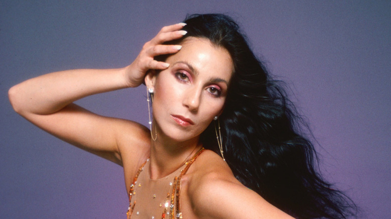 Cher poses in the 1970s wearing a gold glitter jumpsuit