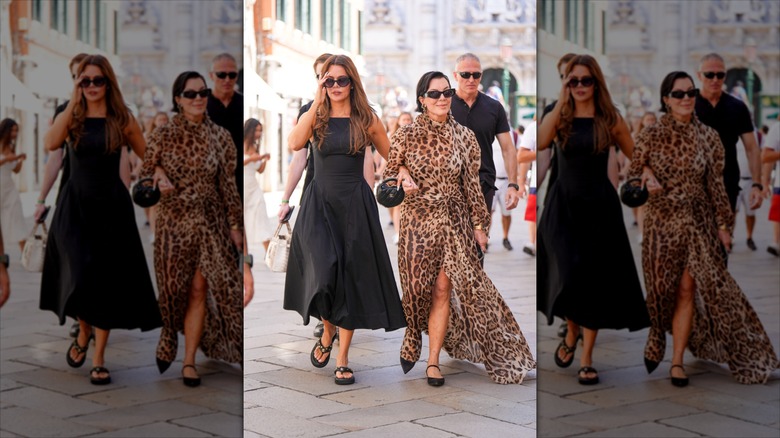 Khloe Kardashian (L) links arms with Kris Jenner (R) wearing a leopard print dress
