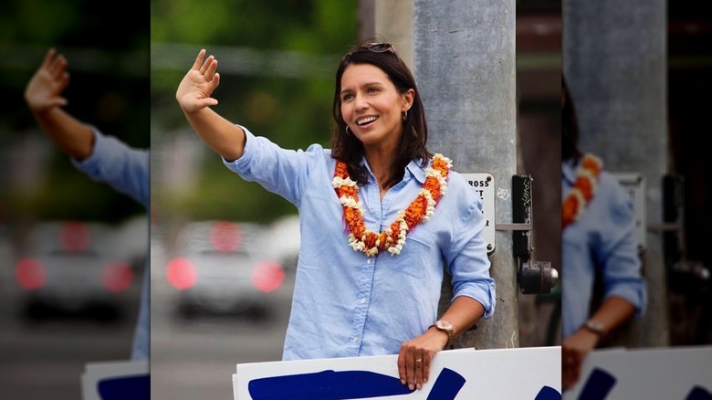 Tulsi Gabbard waving in August 2016, wearing a button-down and a lei