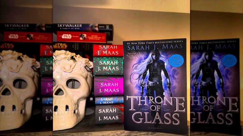 A copy of "Throne of Glass" leaning against a stack of other Sarah J. Maas books