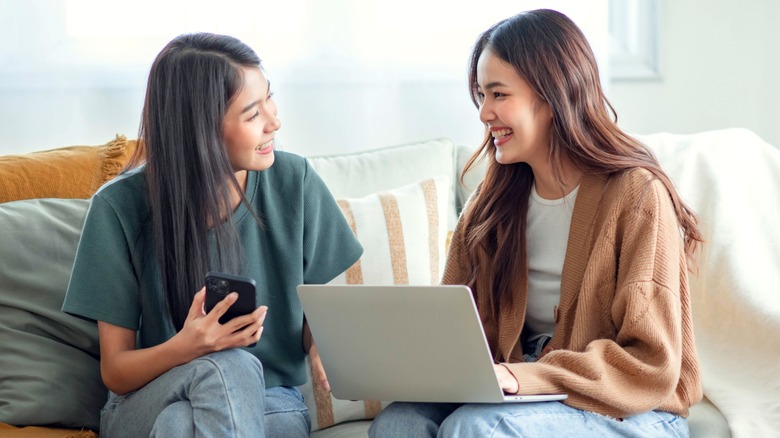 Two women talking, holding gadgets