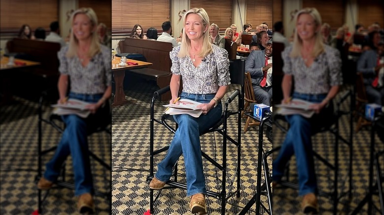 Ainsley Earhardt sitting in a diner, dressed in jeans and chunky brown boots