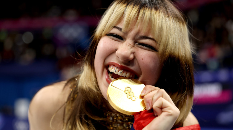 Alysa Liu biting her gold medal in Milan in 2026
