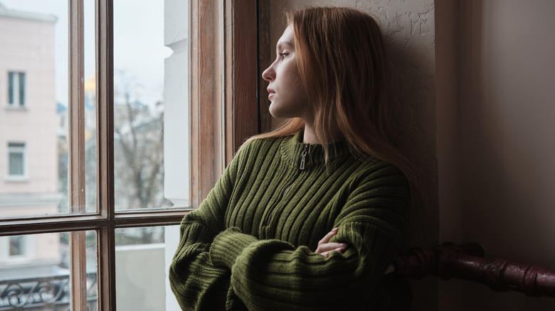 A woman in a green sweater looking out the window