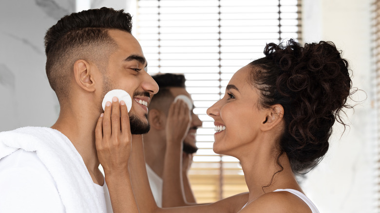 Man and woman washing face together 