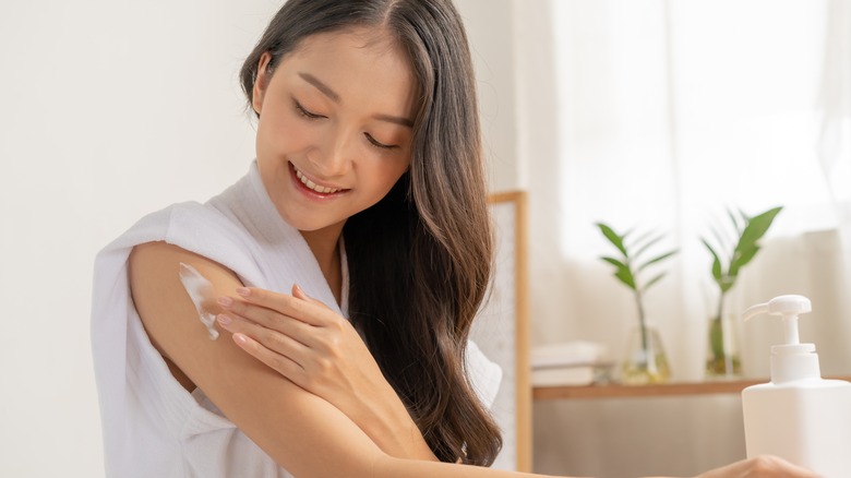 woman applying moisturizer to arm 