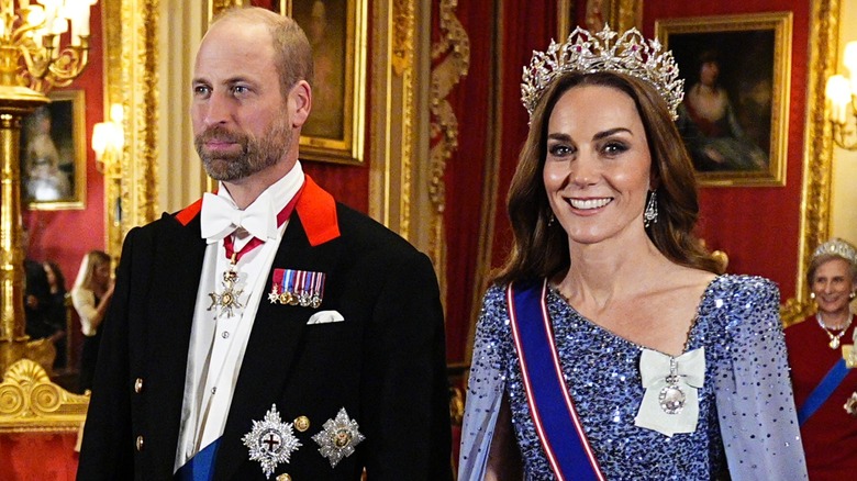 Kate Middleton wearing a large tiara and sequin dress while walking alongside Prince William