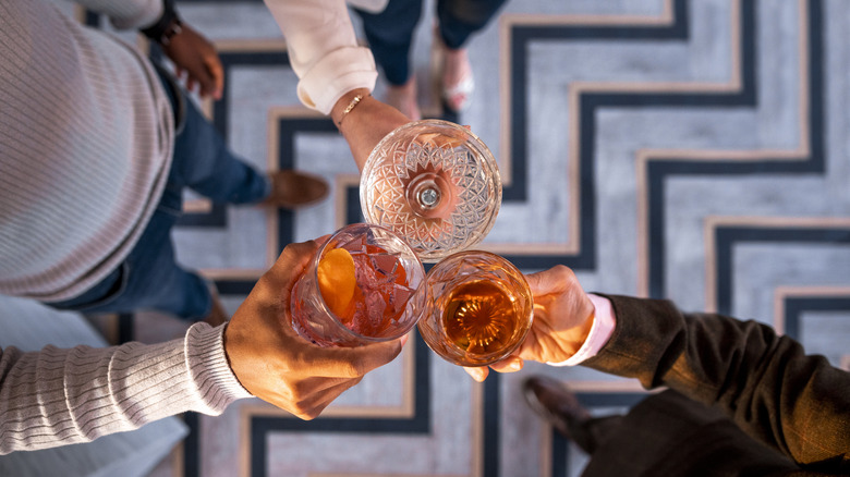 Three people holding alcoholic drinks