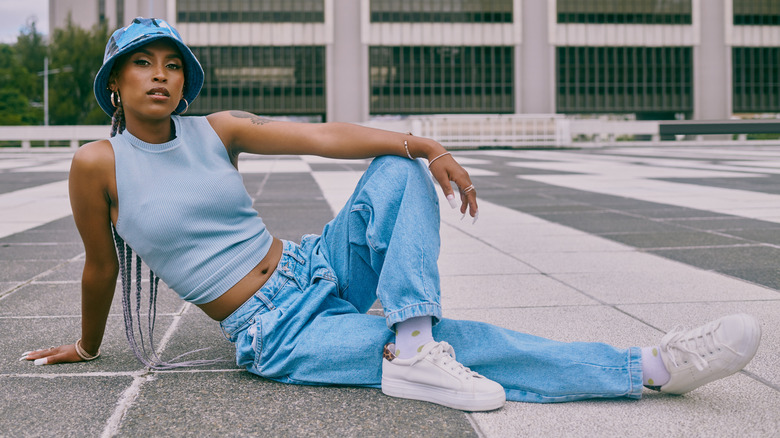 Woman sitting on the ground wearing baggy jeans