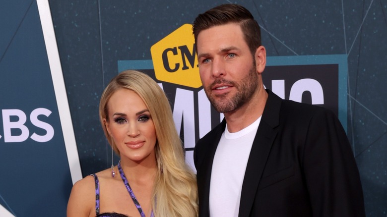 Carrie Underwood and Mike Fisher posing together on the red carpet