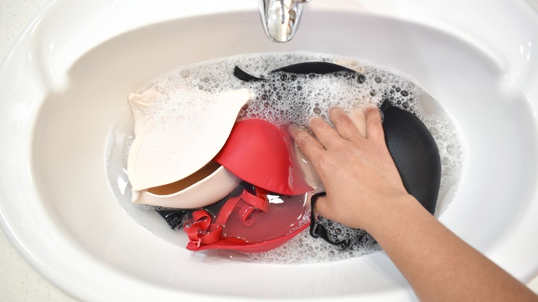 A person washing bras in the sink