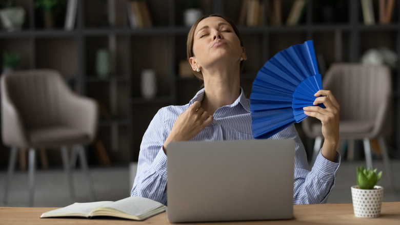 woman fanning herself at work