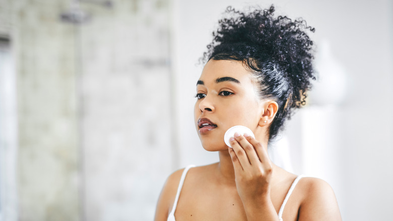 A woman applying toner on her skin