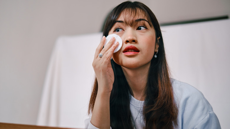 A woman applying toner on her skin