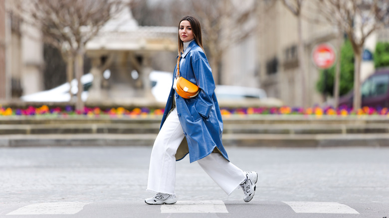 A woman in white sneakers and a long coat 