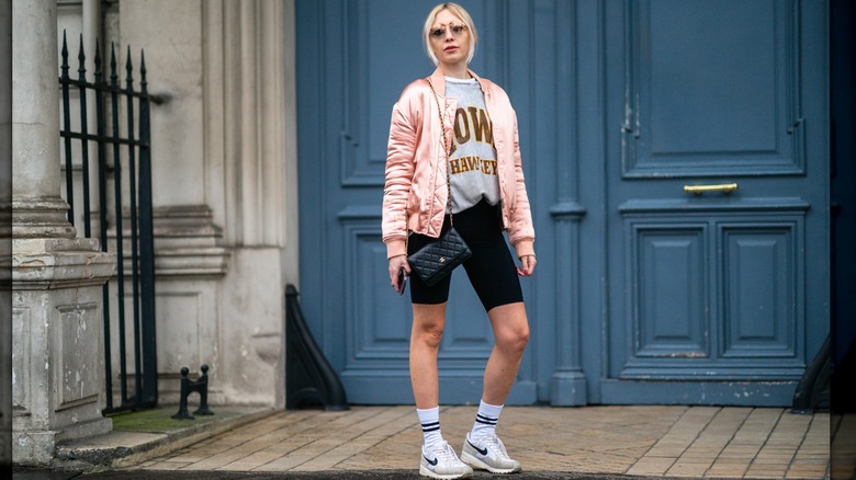 A woman in biker shorts and white sneakers 
