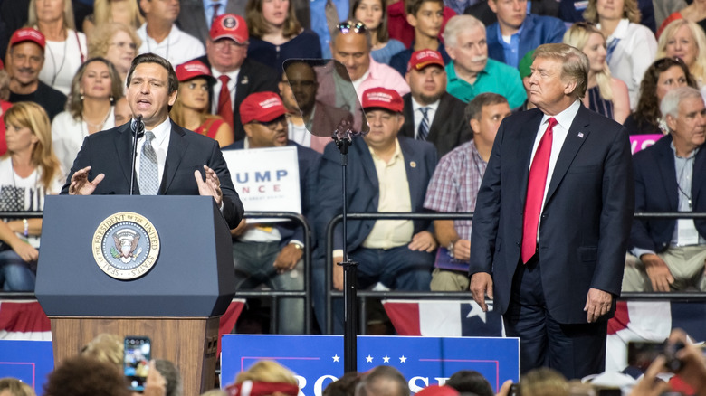 Ron DeSantis and Donald Trump stand on stage while DeSantis speaks to crowd