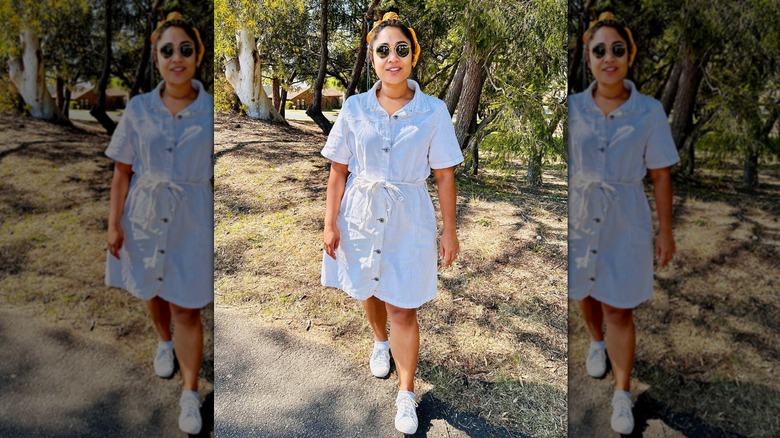 A woman in a white denim dress and white sneakers