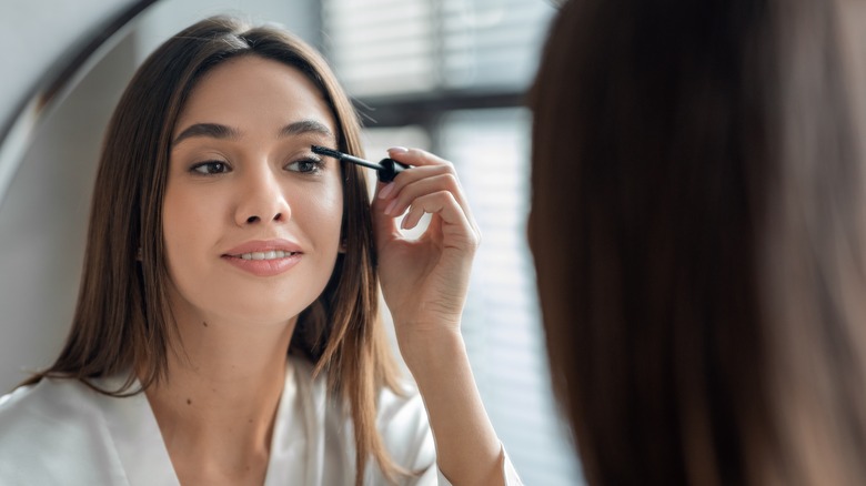 Woman putting on mascara 