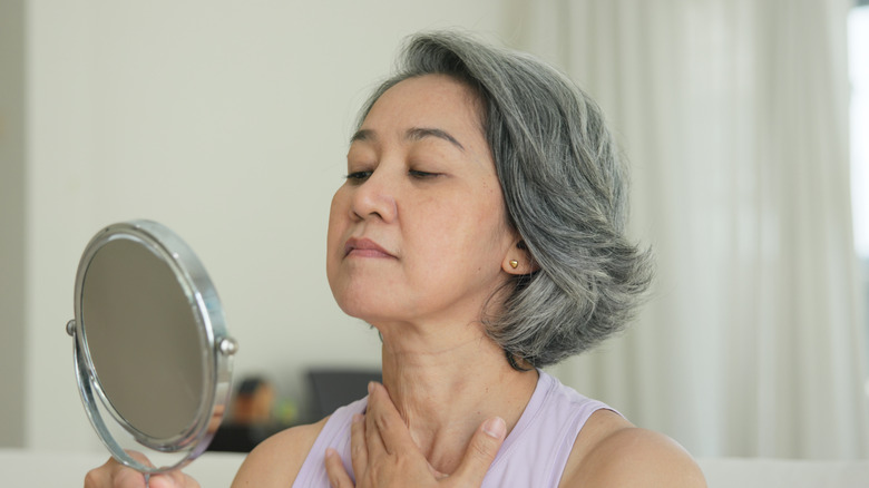 Woman looking at her neck in the mirror