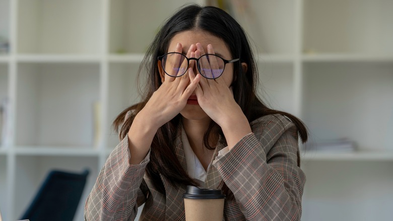 Woman crying covering eyes at desk