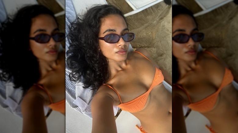 A selfie of Supriya Ganesh wearing sunglasses and an orange bikini