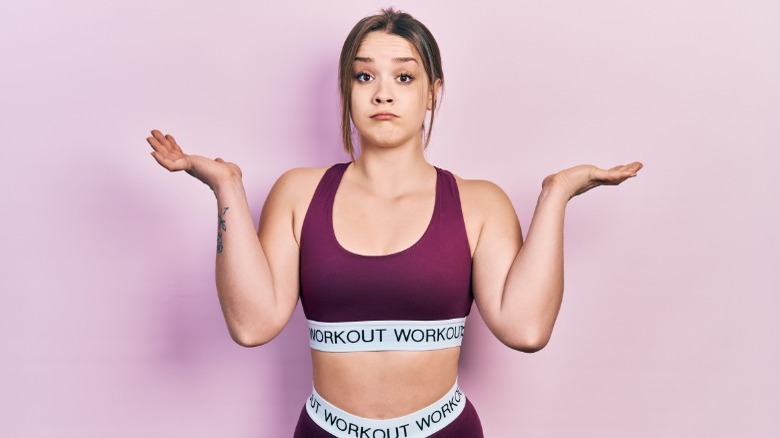 Woman in exercise gear shrugs