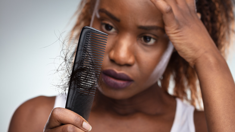 woman with hair loss looking at comb