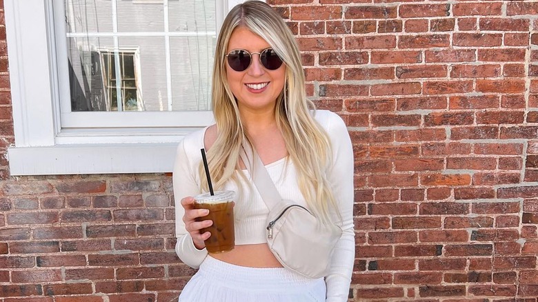 Woman smiling with iced coffee and a belt bag