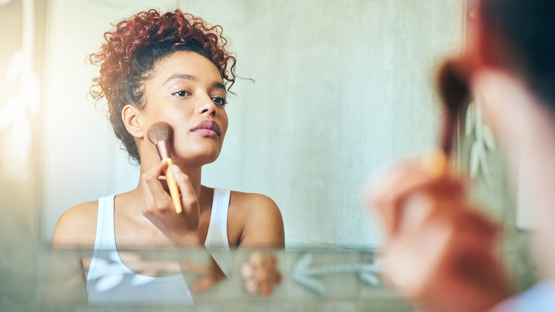 Woman applying blush in mirror