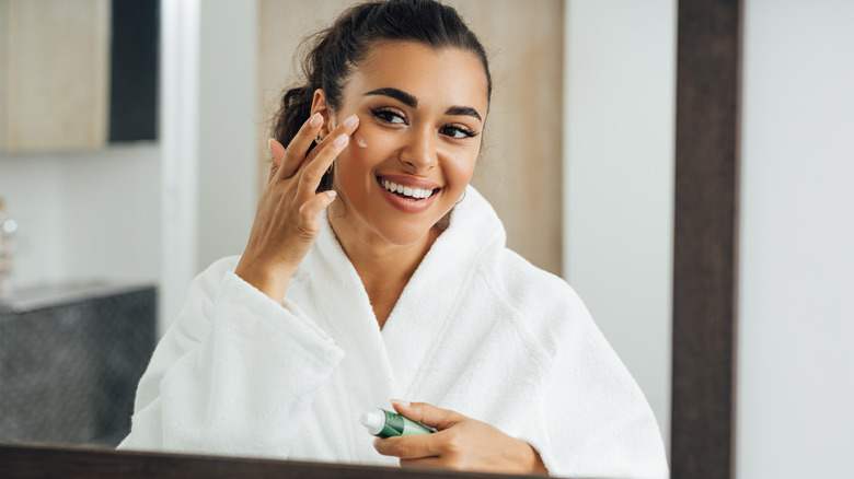 Woman putting lotion on face