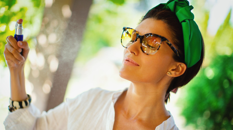 Woman spritzing perfume while outdoors