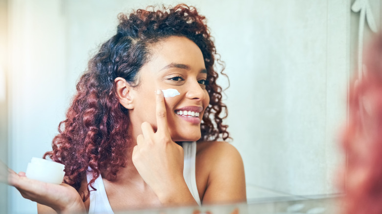 Woman happily applying facial cream