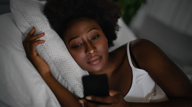 Woman looking at phone in bed