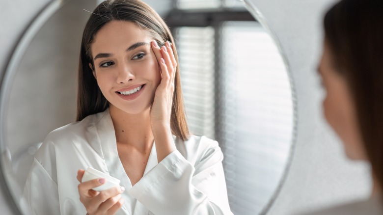 Woman applying skincare from jar