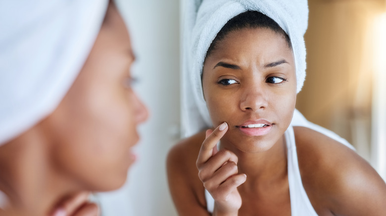 Woman inspecting her skin in mirror
