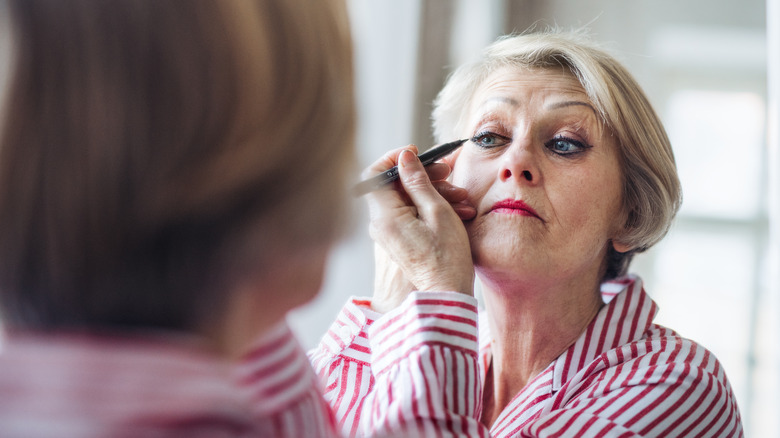 older woman applying eyeliner