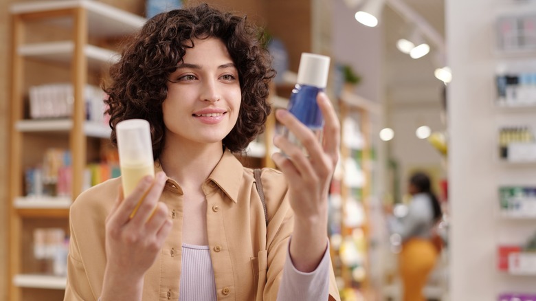Curly-haired brunette woman looking at different beauty products