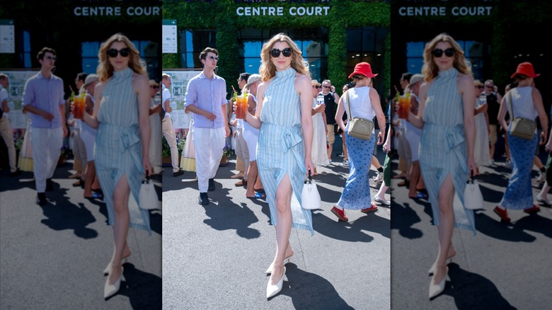 Natalie Dormer wearing sunglasses and a blue halterneck dress while holding a cocktail