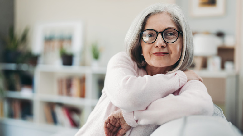 A photo of a mature woman leaning on the back of a couch