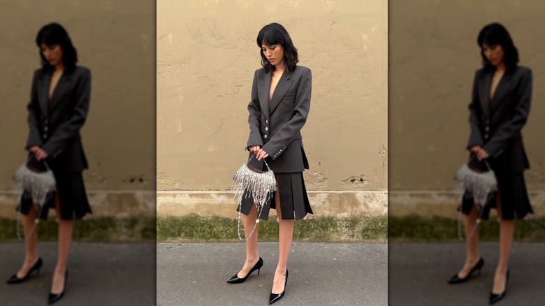 Kelly Asbille wearing a gray suit with sequin bag and black pumps