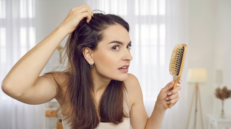 A woman looking at her scalp