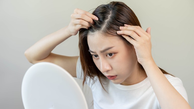 A woman inspecting her scalp