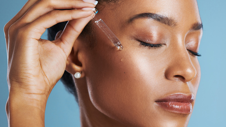 A woman applying face serum