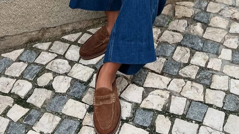 A woman wearing brown suede shoes with jeans