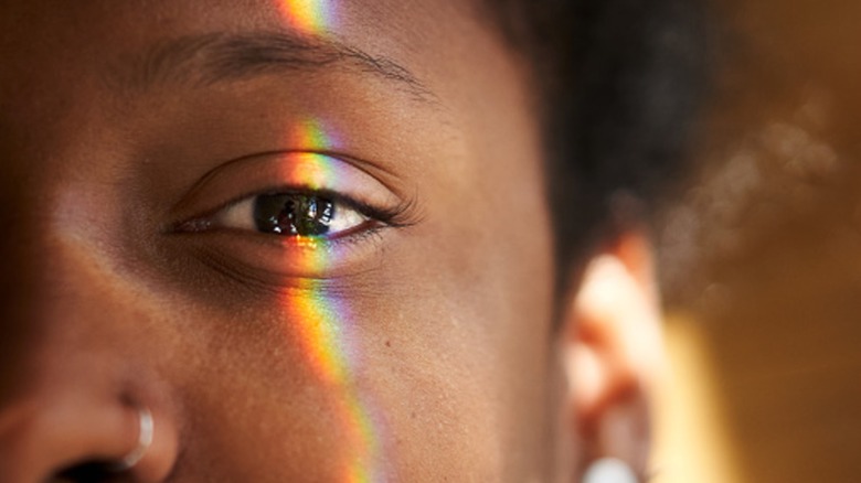 A woman with a brown eye and a rainbow over her face