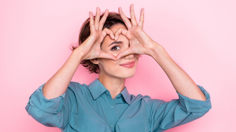 woman making heart around her eye