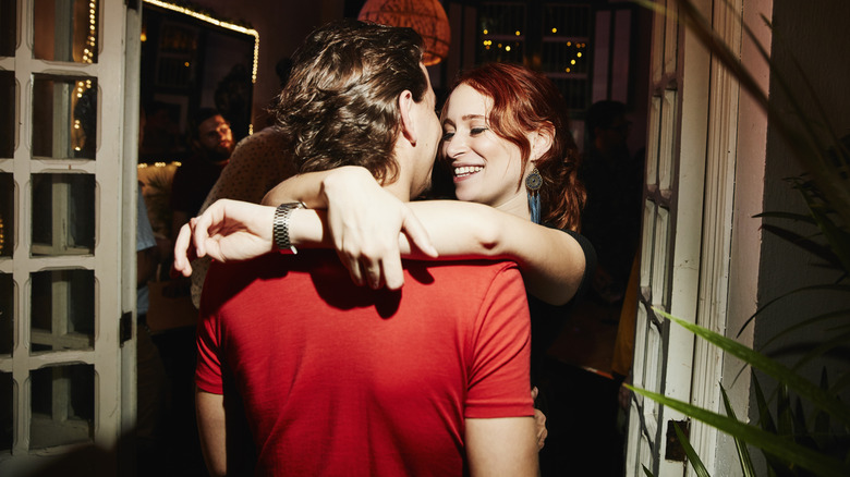 Woman with arms wrapped around another person in a doorway