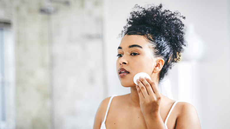 Woman wiping toner on face