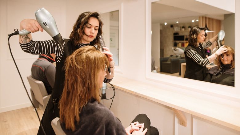 Woman blow-drying a client's hair